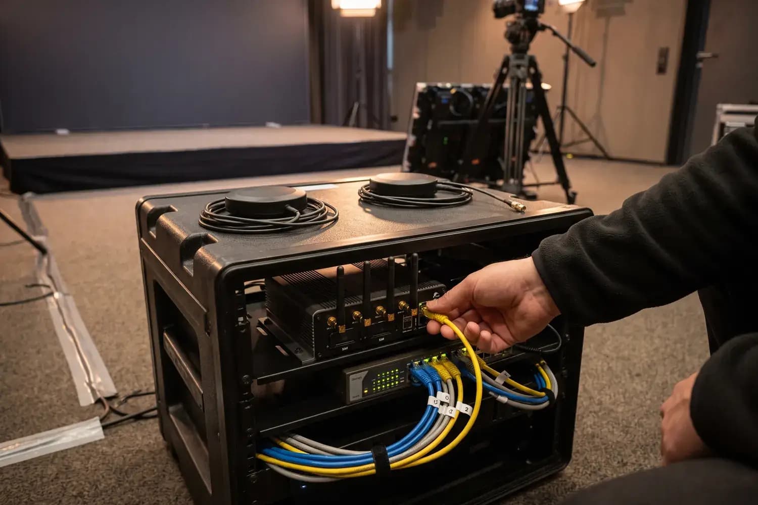 Rack-Case hinter der Bühne: Mobilfunk-Router mit Antennen und Switch, oben zwei 5G-Antennen